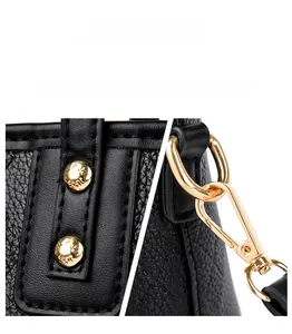 Detailed macro of golden metal lobster clasp and textured rivets on black lychee leather bag