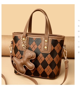 Detail of Argyle patterned tote bag with leather straps and a cute bear charm accessory