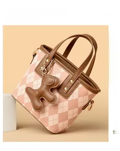 Detail of pink and white diamond lattice bag with brown leather handle and bear charm