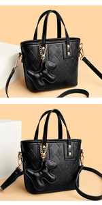 Close-up of black quilted bucket bag with golden hardware and cute dog charm detail