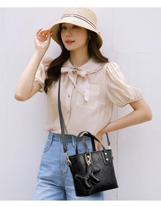 Detail of black quilted bucket bag with golden hardware and cute dog charm on model