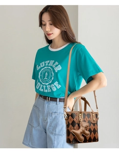 Detail of a brown quilted bucket bag with a dog-shaped charm on a casual outfit