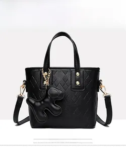 Front view of black lychee grain leather bucket bag with gold hardware and dog charm