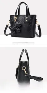 Detail of black pebbled leather bucket bag with diamond lattice pattern and bear charm