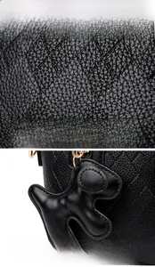 Close-up of black litchi grain leather bucket bag with diamond stitching and dog charm