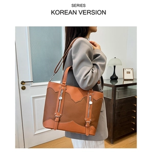Close-up of litchi grain leather tote bag with decorative zippers and buckles