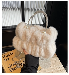 Detail of cream faux fur pleated bag featuring rhinestone handle and pearl accents