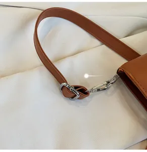 Detail of brown leather tote strap featuring silver metal buckle and reinforced stitching
