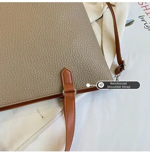 Detail of reinforced shoulder strap stitching on a pebbled leather khaki tote bag