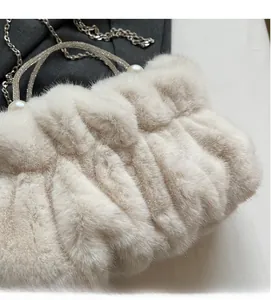 Detail of soft cream faux fur handbag with elegant pearl handle and metal chain strap