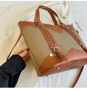 Detail of khaki tote bag showing pebble leather texture and side zipper accents