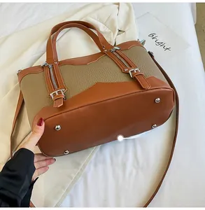 Detailed bottom view of brown color-block tote bag showing four silver metal feet studs