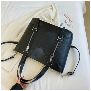 Detail of black pebbled leather tote bag with silver zippers and removable strap