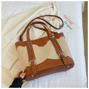 Detail of color-block tote bag featuring western style zippers and leather buckle accents