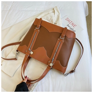 Detailed close-up of brown patchwork tote bag with pebbled leather texture and metal buckle