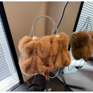 Detail of brown faux rabbit fur bag featuring rhinestone metal handle and pearl accents