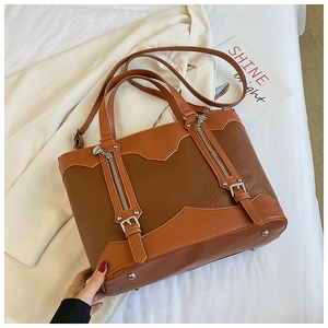 Detail view of large tote bag with lychee pattern leather and bottom protective metal studs