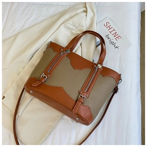 Detail of color-block tote bag with litchi texture and decorative metal zippers