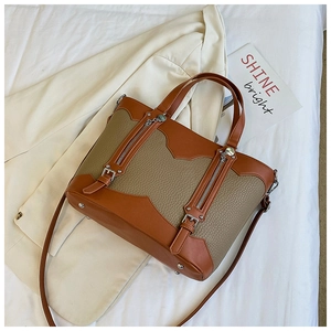 Close-up of color-block tote bag with pebble leather texture and metal zipper details