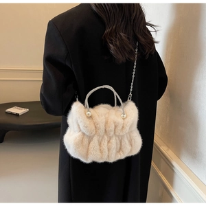 Detail of cream plush shoulder bag with pearl accents and sparkling rhinestone handle