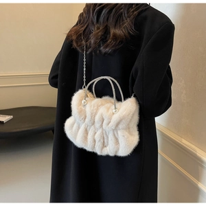 Detailed shot of pleated faux fur handbag with pearl accents and sparkling ring handles