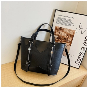 Detail of black patchwork leather tote with pebbled texture and metal zipper accents