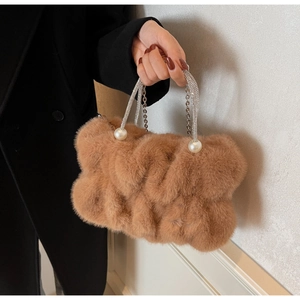 Close-up of plush faux fur handbag featuring crystal-encrusted handle and pearl details