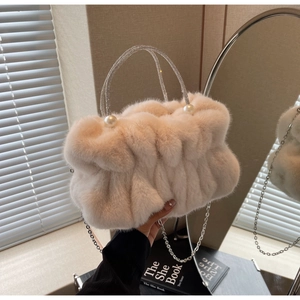 Detail of beige faux fur handbag with pearl clasp and rhinestone handle in soft light