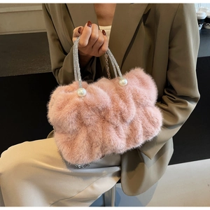Detail of pink faux fur handbag featuring rhinestone handle and pearl accents