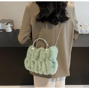 Close-up of light green plush handbag with rhinestone handle and pearl accents