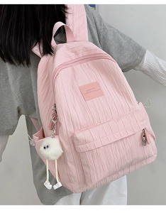 Pink pleated school backpack with front zip pocket and cute white plush monster charm