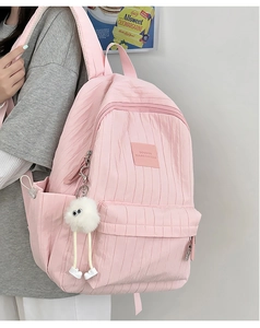 Detail view of pink backpack featuring textured pleated fabric and cute monster pendant
