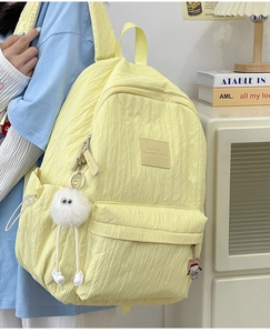 Detail of light yellow backpack featuring unique bubble texture and plush charm