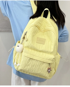 Macro shot of light yellow school backpack showing bubble texture and side drawstring pocket
