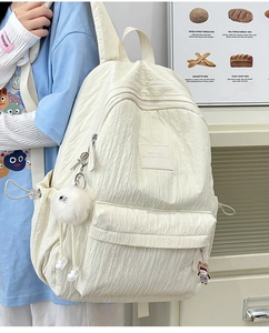 Detail of a creamy white nylon backpack with bubble texture and cute plush charms