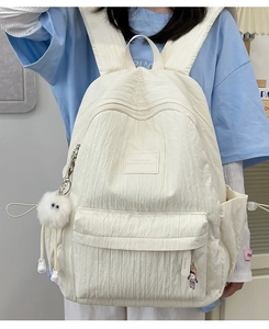 Detail of off-white backpack with pleated texture fabric and cute plush pendants