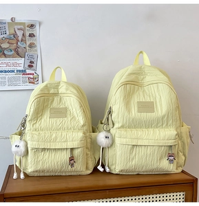 Detail view of two bright yellow pleated nylon backpacks in large and small sizes