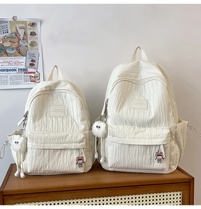 Detailed view of cream bubble textured backpacks in two sizes with cute plush accessories