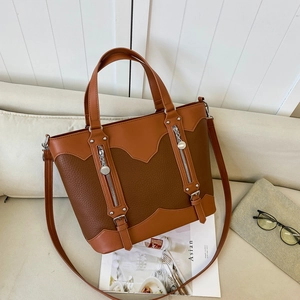 Vintage brown color-block tote bag with handles and crossbody strap on a beige sofa