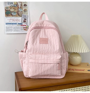 Detailed view of pink backpack featuring textured vertical ripples and leather brand label