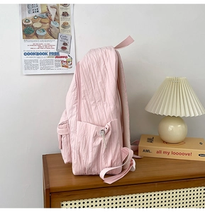 Detailed side view of pink pleated backpack showing drawstring pocket and mesh straps