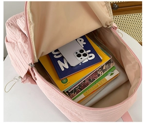 Detail view of pink backpack's spacious main compartment showing books and electronics