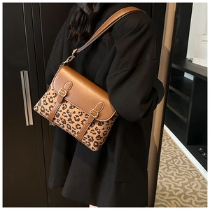 Leopard print crossbody bag with brown leather details worn by a model in a black coat