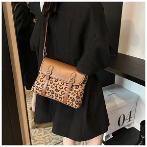 Detail of a brown leopard print crossbody bag with double buckle straps and PU leather finish