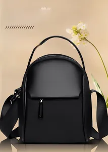 Detail view of the black nylon crossbody bag with dual zippers and adjustable strap