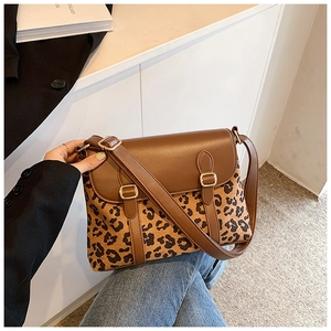 Detailed view of brown crossbody bag with leopard print panel and golden buckles