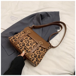 Detail of leopard print crossbody bag with brown leather trim and gold buckles on a blazer