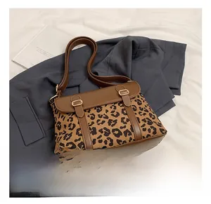 Detail of leopard print crossbody bag featuring gold buckles and brown faux leather trim