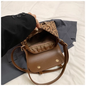 Detail of leopard print messenger bag featuring magnetic closure and striped inner lining