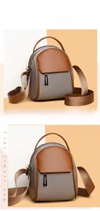 Detail view of the gray nylon fabric and brown leather flap on a small crossbody bag